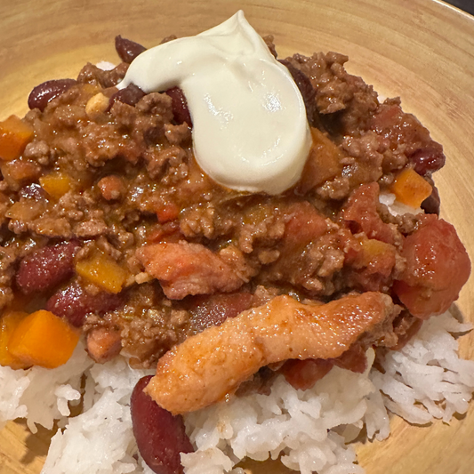 a bowl filled with rice with chilli con carne topped with sour cream