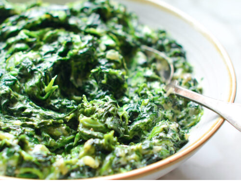 Creamy tamarind spinach served in a shallow bowl, featuring vibrant green cooked spinach folded into a rich, tangy cream sauce — Filipino-inspired creamed spinach side dish using tamarind jam.